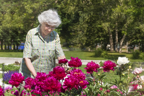 Senior woman with peonies flowers in a park  © boryanam