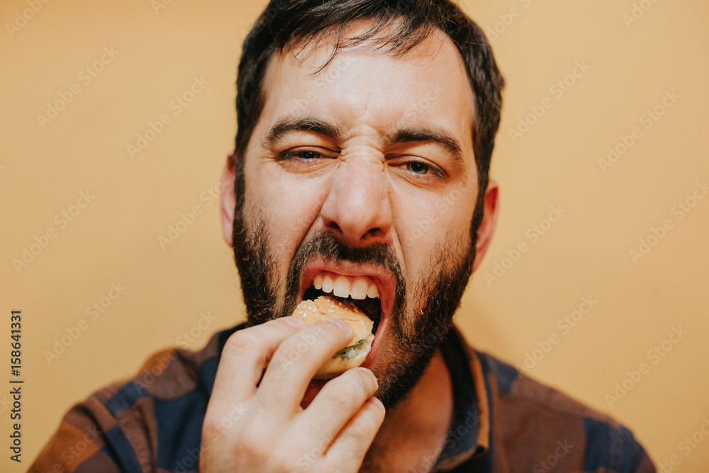 Young man eating a burguer with a funny expression. Lifestyle portrait. Young man eating a burguer with a funny expression. Lifestyle portrait.