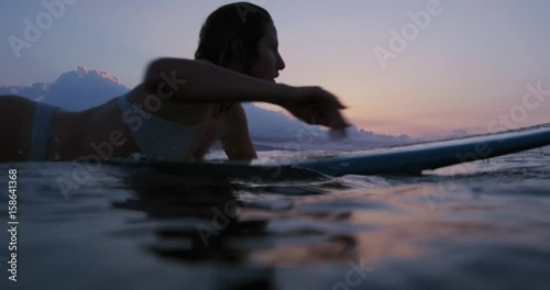 Beautiful young woman surfing in bikini at sunset in slow motion