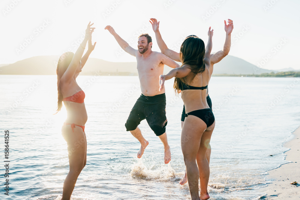 Group of friends millennials having fun on the beach - togetherness, outdoor activities, getting away from it all concept Group of friends millennials having fun on the beach - togetherness, outdoor activities, getting away from it all concept