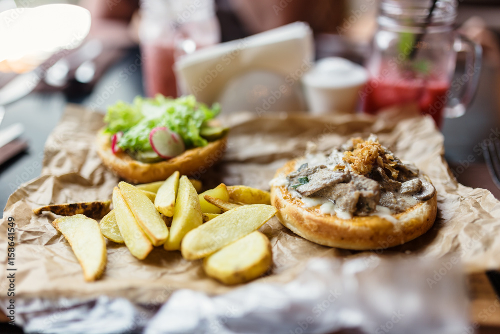 Burger with pieces of beef, fried onions, potatoes and vegetables.