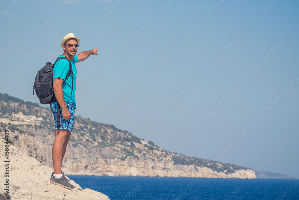 Hiker with backpack on the top of the hill above the sea. Freedom and active lifestyle concepts.