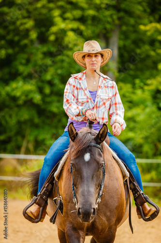 Cowgirl doing horse riding on countryside meadow