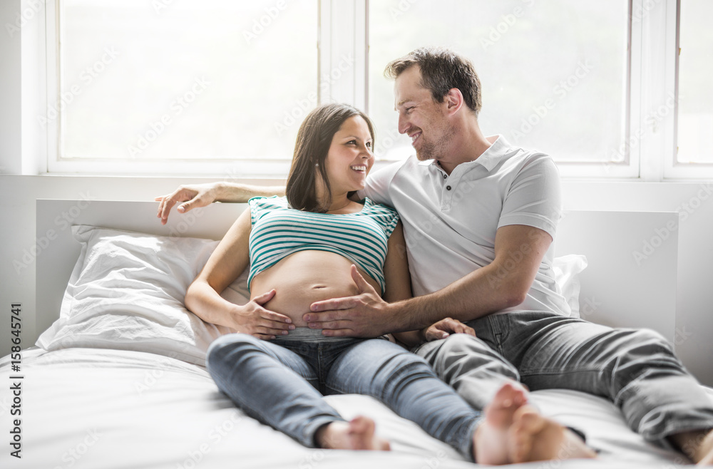 Young parents in bed expecting a little baby, Romantic moments for pregnant couple Young parents in bed expecting a little baby, Romantic moments for pregnant couple