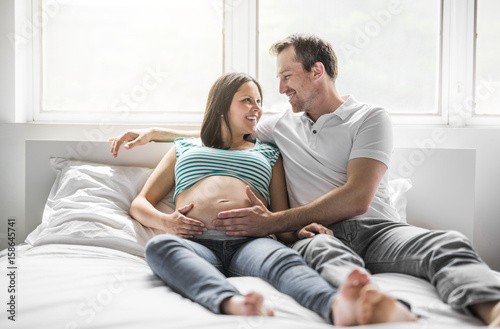 Young parents in bed expecting a little baby, Romantic moments for pregnant couple