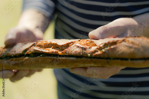 Garlic and fresh herbs olive oil baguette in man hands, outdoors party