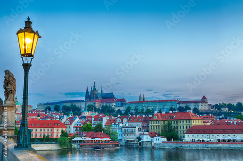 View of Prague Castle, mala Strana and Vltava river in Prague from Charles Bridge with street lamp during blue hour sunrise photo