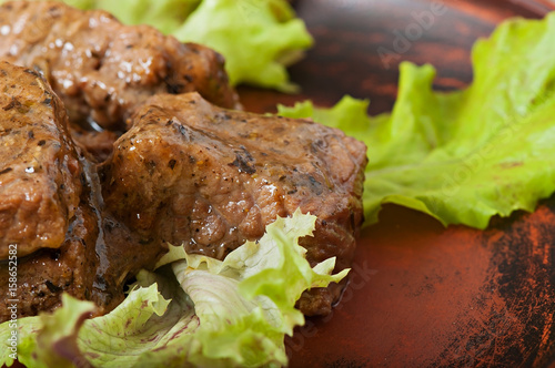 Freshly prepared juicy stewed veal with spicy sauce decorated with lettuce leaves.