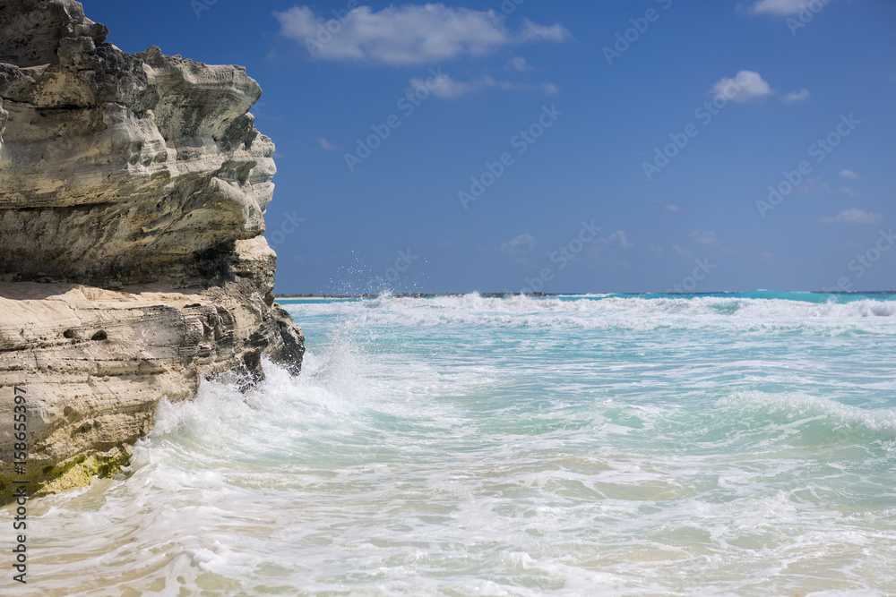 Coastline on the Caribbean sea shore. Wave hitting the big cliff.