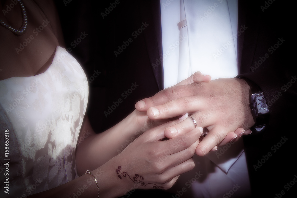 Fototapeta premium Close up hands of bride and groom putting on a wedding rings