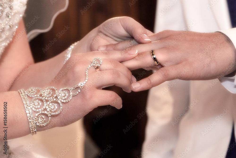 Close-up hands of bride and groom putting on a wedding rings
