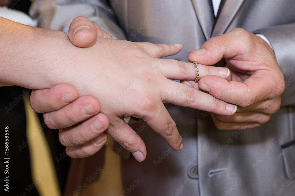 Close-up hands of bride and groom putting on a wedding rings