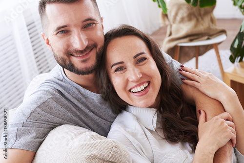 Pleased girl and boy hugging and relaxing on sofa