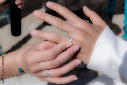 Close-up hands of bride and groom putting on a wedding rings © NizArt