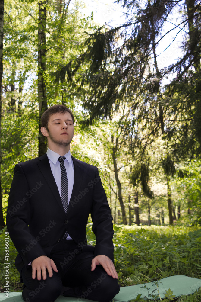 Businessman meditating in nature. A man in a business suit sits in the woods in a diamond pose and meditation. Businessman meditating in nature. A man in a business suit sits in the woods in a diamond pose and meditation.