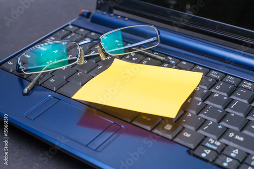 sticky note and sunglasses on a laptop keyboard