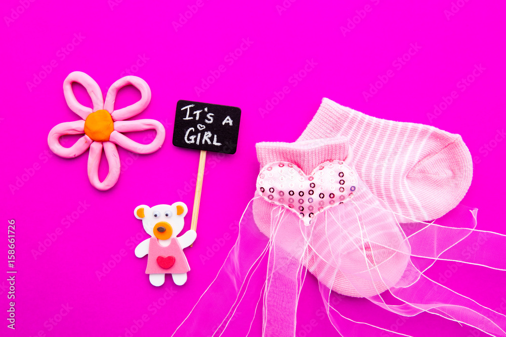 Baby Girl announcement - pink and white socks with bear on pink background with It's a Girl blackboard sign
