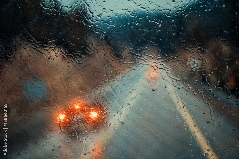 Fototapeta premium blurry cars and lights in traffic in a rainy evening seen through windscreen