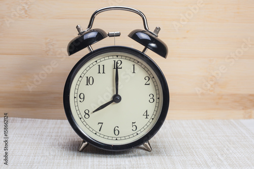 analog clock at 8 o clock over wooden background
