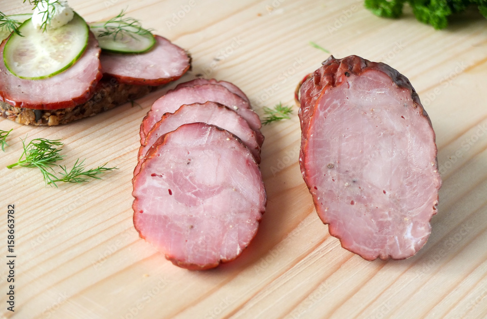 Smoked sausage, ham on a wooden board Smoked sausage, ham on a wooden board