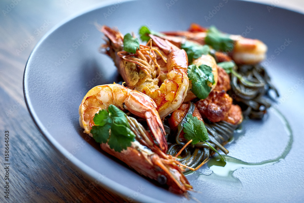 Cooked shrimps,prawns with seasonings on stone background. Fried shrimp with rosemary in a portioned frying pan on a dark table top view. Cooked shrimps,prawns with seasonings on stone background. Fried shrimp with rosemary in a portioned frying pan on a dark table top view.