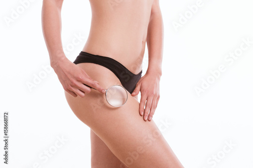 Woman checking cellulite with magnifying glass 