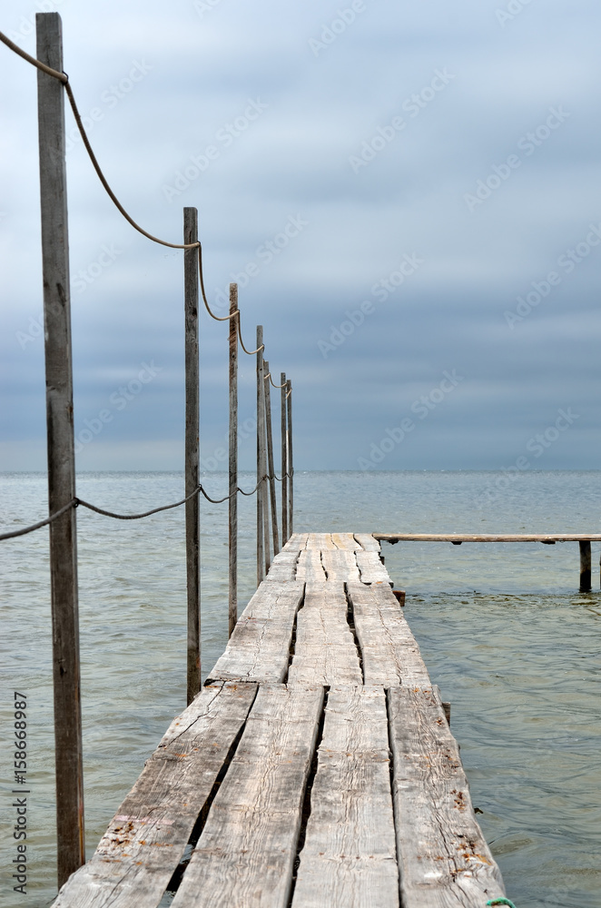 Wooden laying on a background of blue sea. Boardwalk pier on the beach.