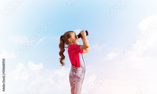 Concept of careless happy childhood with girl looking in binoculars