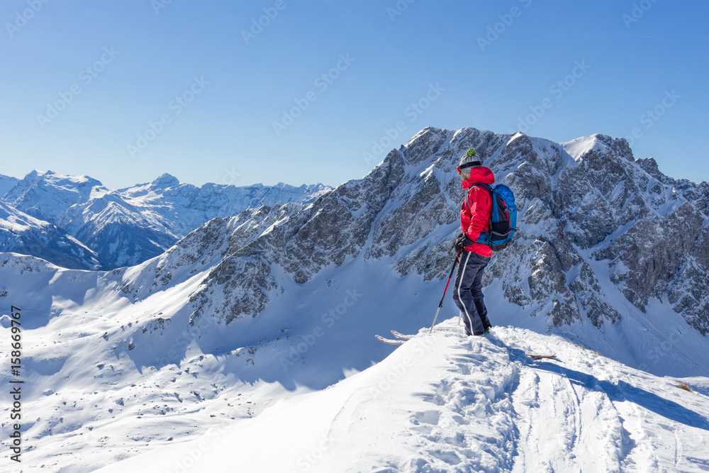 Mountaineer with skiers enjoying the view in the mountains in winter