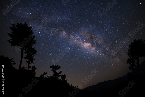 Landscape with milky way, Night sky with stars and silhouette of tree, Long exposure photograph, with grain.