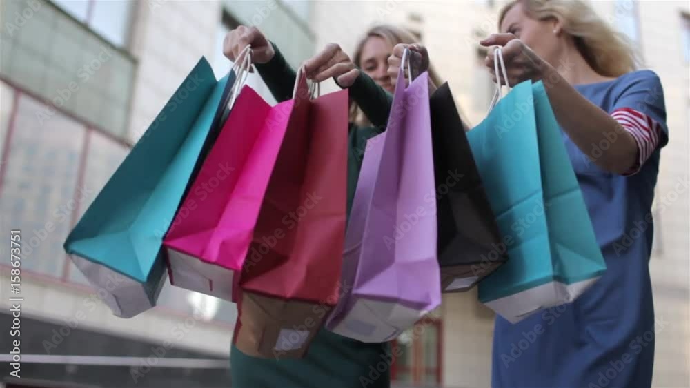 Close-Up, Two Girls Holding a Bunch of Shopping Bags on the Street Close-Up, Two Girls Holding a Bunch of Shopping Bags on the Street