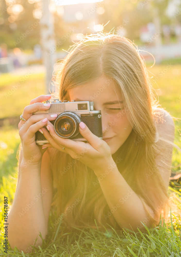 woman the photographer with old camera lays on a grass woman the photographer with old camera lays on a grass