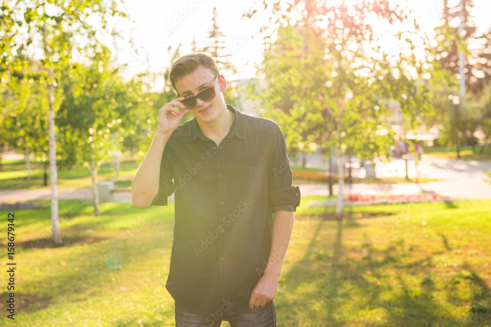 Handsome stylish hipster man in sunglasses posing at sunshine nature, enjoying beautiful view Handsome stylish hipster man in sunglasses posing at sunshine nature, enjoying beautiful view
