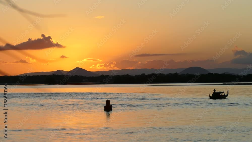 Silhouette of a gondola boat passing by a sunset over mountains. Silhouette of a gondola boat passing by a sunset over mountains.