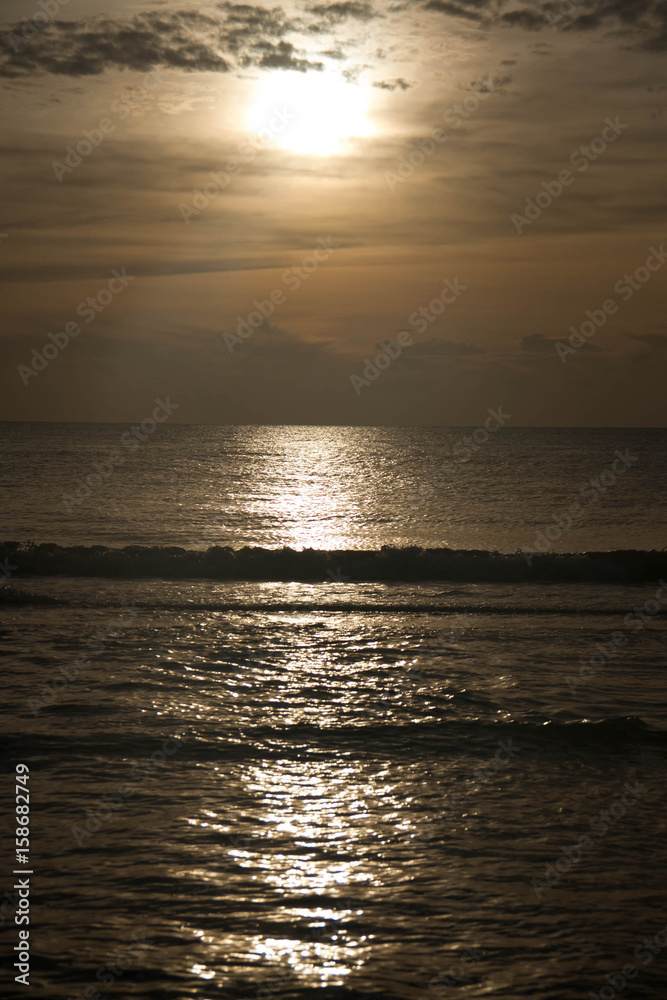 Sunrise reflects on the dark waving ocean