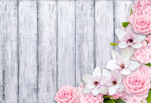 Magnolia flowers with roses and hortense on background of shabby wooden planks in rustic style