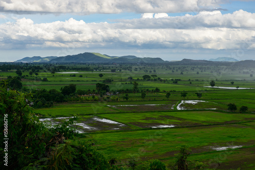 landscape panorama with view of green field and mountains on rainy day