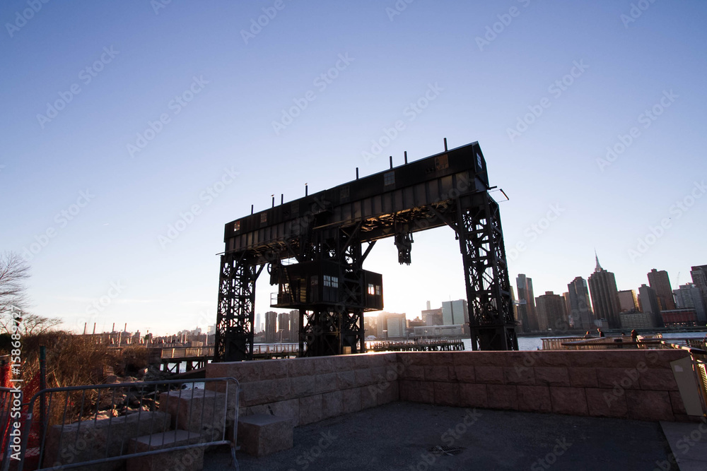 Transfer bridges, support gantries, and piers at Gantry Plaza State Park in silhouette before sunset