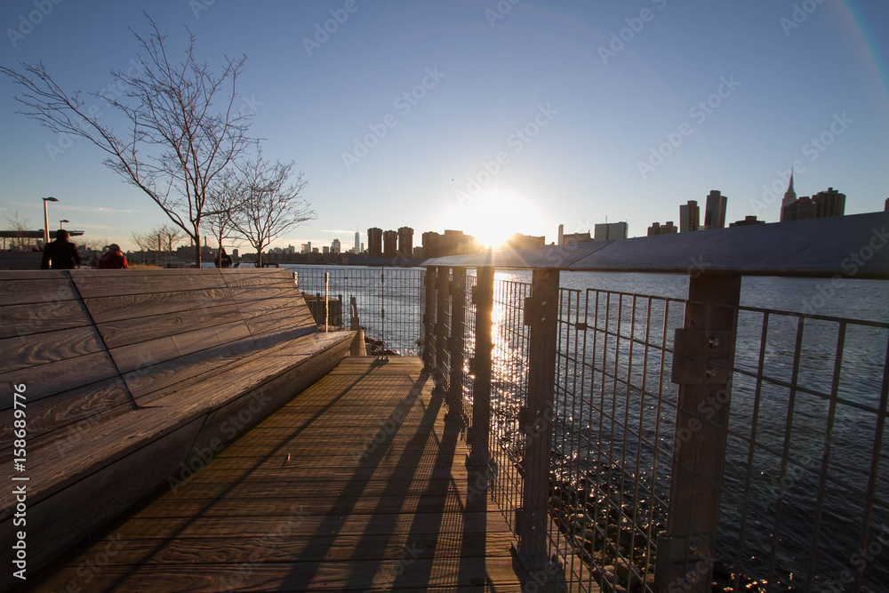 Fence and seat next to river with sunset