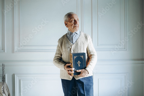 Grandfather praying, holding Bible,