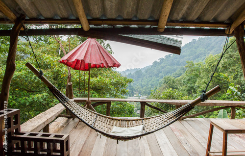 Empty wooden hammock outside the terrace with jungle background in Chiang Mail, Thailand