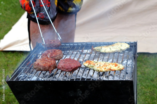 Chicken and beefburgers cooking on a traditional lumpwood charcoal barbecue photo