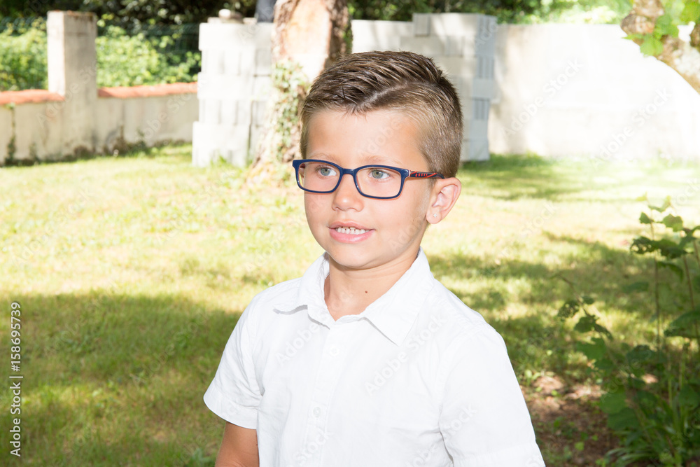 young blond boy in the family garden with glasses young blond boy in the family garden with glasses