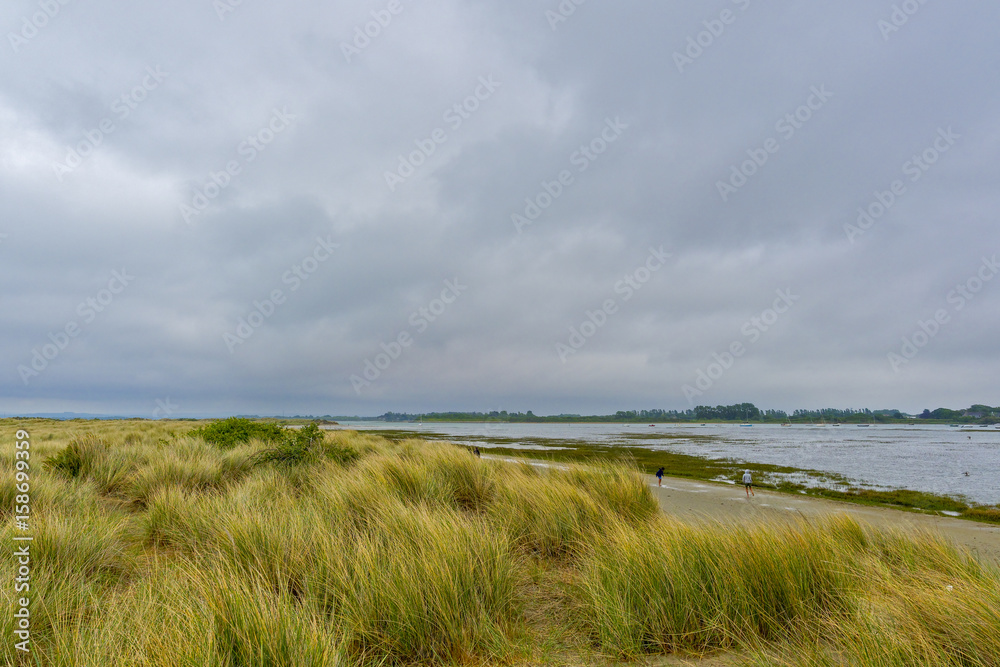 Salt marshes surrounding a large lake on the coast near West Wittering on a gloomy afternoon.