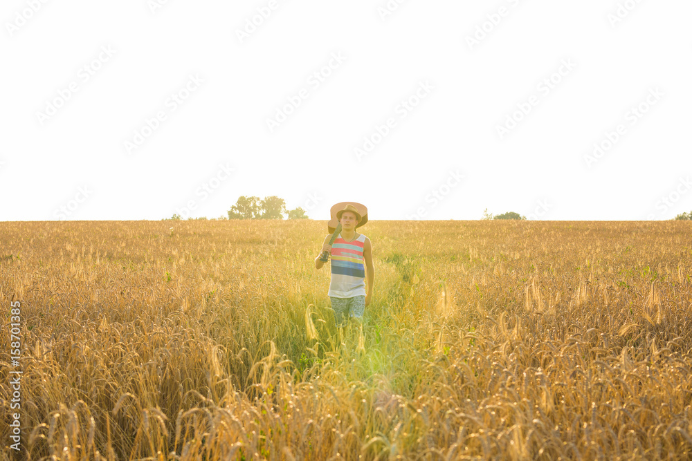 Musician holding acoustic guitar and walking in summer fields at sunset Musician holding acoustic guitar and walking in summer fields at sunset