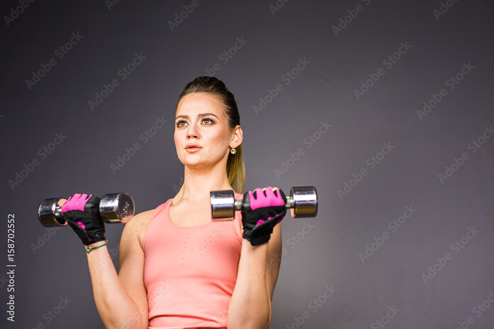 Athletic woman doing exercises with dumbbells in the gym.