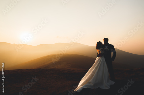 Happy beautiful wedding couple bride and groom at wedding day outdoors on the mountains rock. Happy marriage couple outdoors on nature, soft sunny lights photo