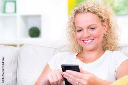 Hübsche Frau schreibt sms auf Couch