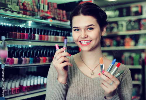 Smiling woman customer browsing rows of lipstick