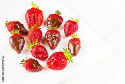 Strawberries dipped in delicious chocolate in white dish isolated on white background. Close up view.